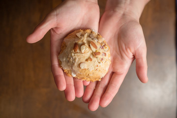 female hands holding out iced scone with almond slivers
