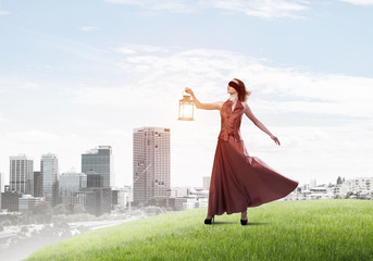 Attractive girl muse with old lantern in hand at summer day
