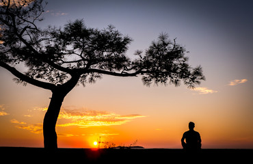 a man looks at the sunrise on the desert shore of the sea