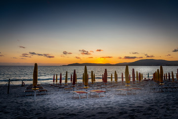 Beach chairs and parasols under a clear sky at sunset