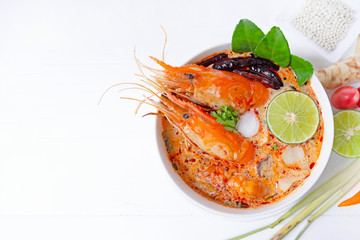 Tom Yum Goong or Shrimp soup spicy sour Soup Traditional food in Thailand contains chili, lime, ginger, galangal, lemongrass, lime leaf,  white wood background.
