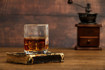 Whiskey with ice or brandy in a glass and a square carafe on an old wooden background. Whiskey with...