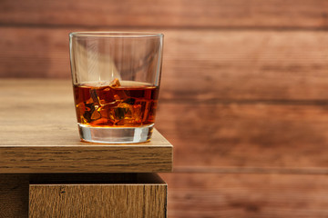 Whiskey with ice or brandy in a glass and a square carafe on an old wooden background. Whiskey with...