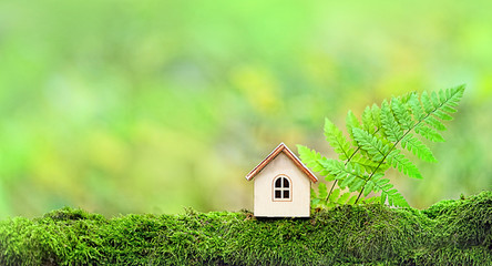 Wooden toy house in nature green summer landscape. Symbol of happiness, family, Mortgage, Real estate concept. Eco Friendly House.  creative minimalism design. copy space