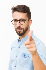 Serious determined guy pointing finger at camera. Handsome young man in casual shirt and glasses...
