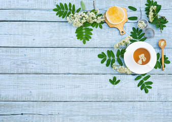 Fototapeta na wymiar Healthy Herbal Flower tea. Tea cup with Rowan Flowers (Sorbus aucuparia), leaves and Crystal Sugar on wooden table. Herbal Medicine. Phytotherapy Medicinal Herbs. Copy space