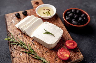 feta cheese, with rosemary, tomatoes, olives on a stone background