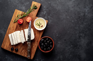 feta cheese, with rosemary, tomatoes, olives on a stone background. top view with copy space for your text