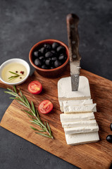 feta cheese, with rosemary, tomatoes, olives on a stone background