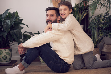 Father and son looking at camera. Dad giving piggyback ride to the boy. close up