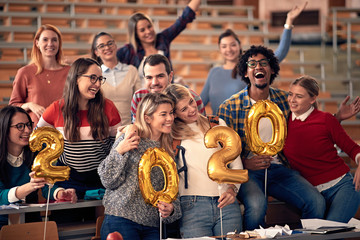 happy students celebrating 2020 new year toghether in university - obrazy, fototapety, plakaty