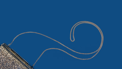 Festive evening golden clutch on classic blue paper drop. Holiday and celebration background. Luxury accessories and party concept. Christmas and New Year Celebration. Horizontal, wide screen