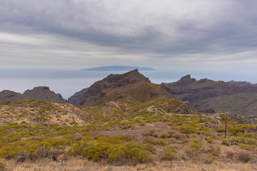 Carretera hacia Masca, en el Macizo de Teno, e isla de la Gomera al fondo (Tenerife, Islas Canarias - España).