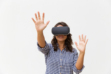 Happy student girl in VR goggles touching air. Young woman in virtual reality headset standing isolated over white background. VR experience concept