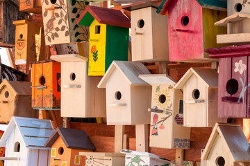 Obraz na płótnie Canvas Birdhouses made with their own hands from wood and painted in different colors. Colorful bird houses in a large number of outdoor