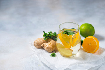 Ginger-lemon drink. Homemade Organic ginger in a glass with Lemon and mint on white table. Trendy detox healthy drink.