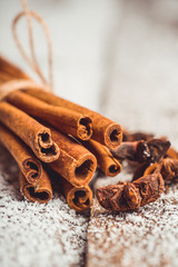 Christmas setting with bundle of cinnamon, anise stars and other christmas decorations on the rustic wooden background. Selective focus. Shallow depth of field.