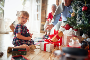 Obraz na płótnie Canvas Cute little blonde girl holding her Christmas present