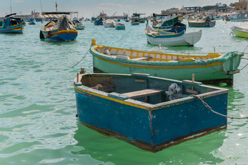 Fototapeta na wymiar Traditional aged boats in Marsaxlokk village harbor in Malta