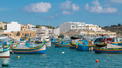 Fototapeta na wymiar Colorful, traditional fishing boats in Marsaxlokk village harbor of Mediterranean island of Malta