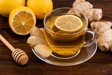 Cup of Ginger tea with lemon, honey and ginger root on a wooden background