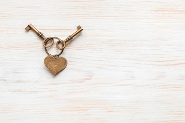 Bronze color keys and heart together lying on wooden board. Space for text.