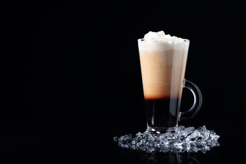 Cold coffee drink or cocktail with cream on a black background.