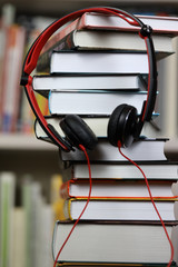 headphones and a stack of books, listening to audio books and traditional reading