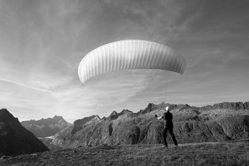 Young paraglider pilot exercises with his paraglider pulling up in the wind, the so-called ground handling. Near Grimsel in the Swiss Alps