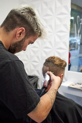 Fototapeta premium hairdresser cutting hair to man with electric razor