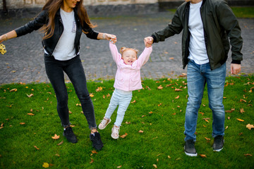 Happy family playing on the green lawn raising baby hands