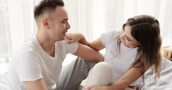 Young couple having fun talking in bed at home