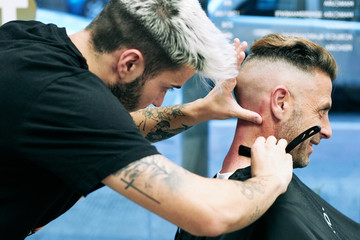 hairdresser cutting hair to man with traditional razor