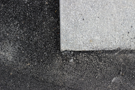 Dark new asphalt surface surrounding marble tile detail texture 
