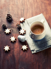 Obraz na płótnie Canvas Mug of coffee and Christmas cookies (cinnamon stars) on rustic wooden background. Copy space.