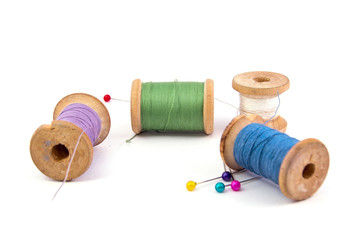 green blue purple white sewing threads and colored needles on white background isolated
