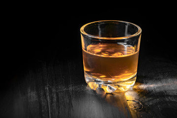 single glass of cognac on a black tree