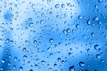 Raindrops on the glass closeup. Color of the year 2020. Bright beautiful background of trendy blue color. Place for text. Delicate classic backdrop. Water drop texture. Fashionable shades.