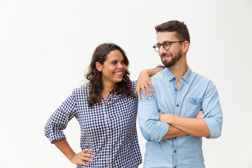 Cheerful couple standing close together, chatting and laughing. Young woman in casual and man in...