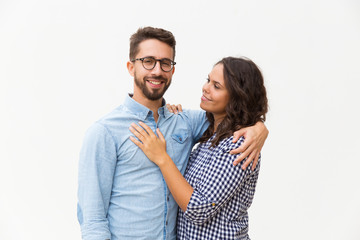Naklejka premium Positive united family couple hugging, talking and posing for camera. Young woman in casual and man in glasses standing isolated over white background. Relationship and bonding concept