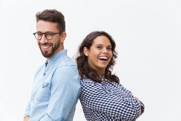 Happy cheerful couple leaning on each other, laughing and looking at camera. Young woman in casual and man in glasses in glasses posing isolated over white background. Close friendship concept