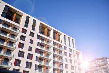 Fototapeta premium Modern apartment buildings on a sunny day with a blue sky. Facade of a modern apartment building. Glass surface with sunlight.