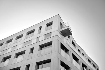 Detail of modern residential flat apartment building exterior. Fragment of new luxury house and home complex. Glass surface with sunlight. Black and white.