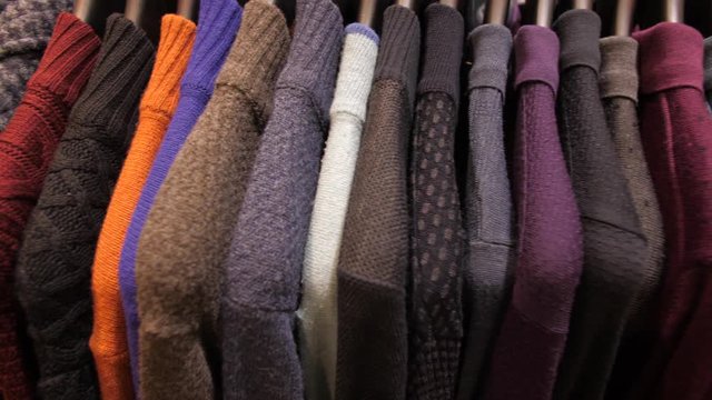 Sweaters on hangers at clothing store