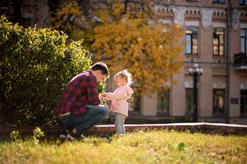 Father playing with daughter finding an autumn leaves in the park