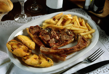 Un Plato con costillas de cordero, Berenjenas rebozadas y patatas fritas.