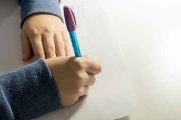  girl writes  in pencil in a notebook