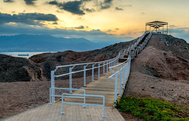 Scenic point of view with decorative pergola and safe walkway to the stone summit in public park of Eilat - famous tourist resort and recreational city in Israel