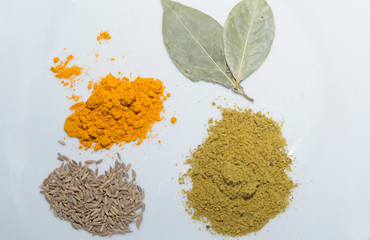 seasonings on a white leaf in bulk: turmeric, cumin, hops suneli, Bay leaf
