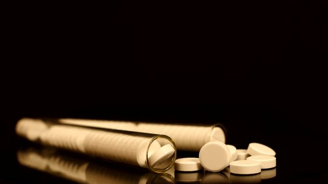 Generic drugs on table top, camera moves slowly accross spilled pills and into the bottle.